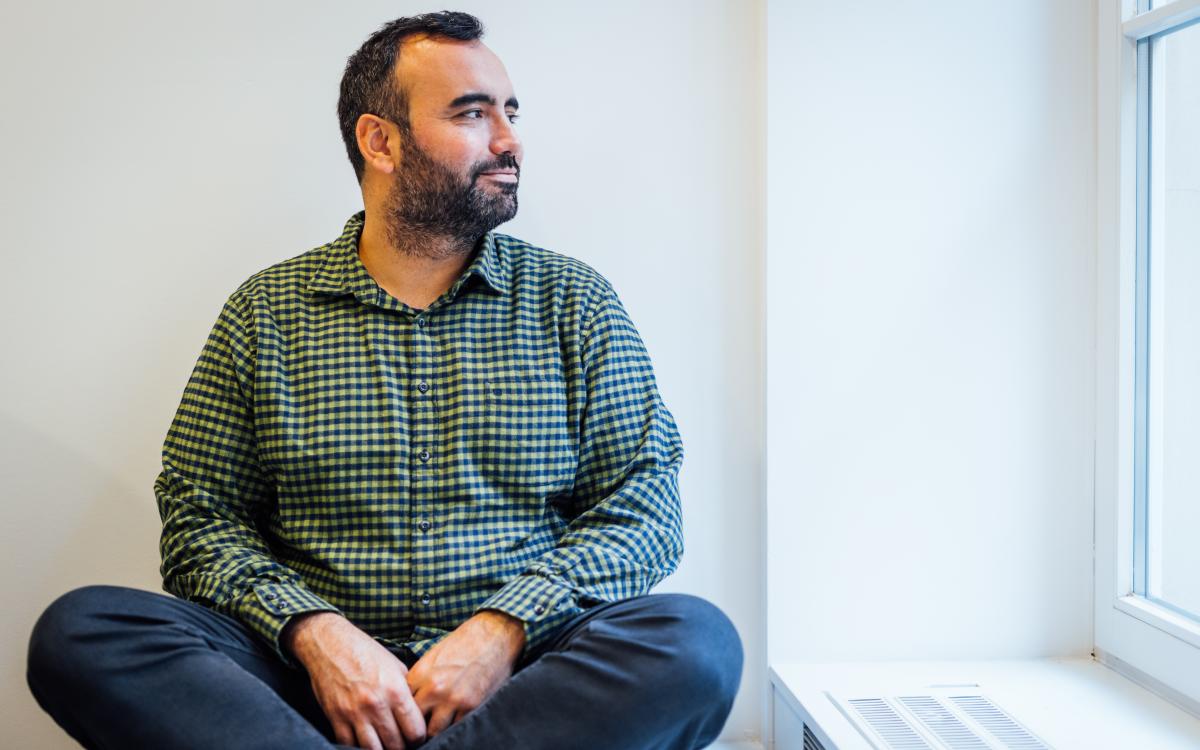 man sitting cross legged looking out the window