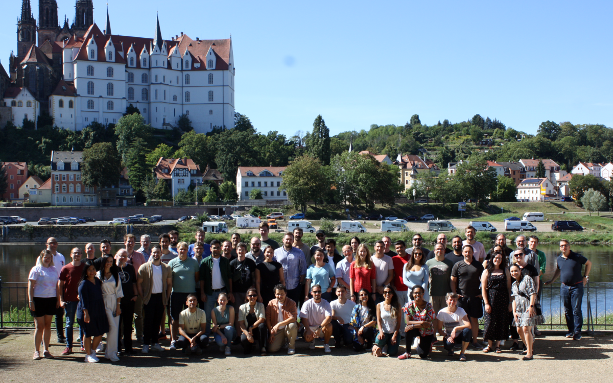 group of people standing in front of a river and a castle