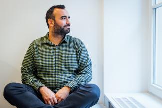 man sitting cross legged looking out the window