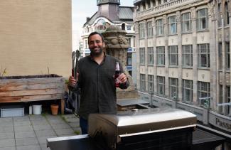 man standing behind a grill on a balcony