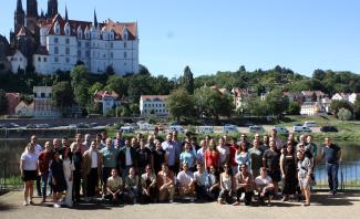 group of people standing in front of a river and a castle